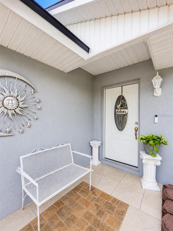 A front porch features a white metal bench, two decorative pedestals, and a white door — 1822 S HOUSTON DR, DELTONA, FL