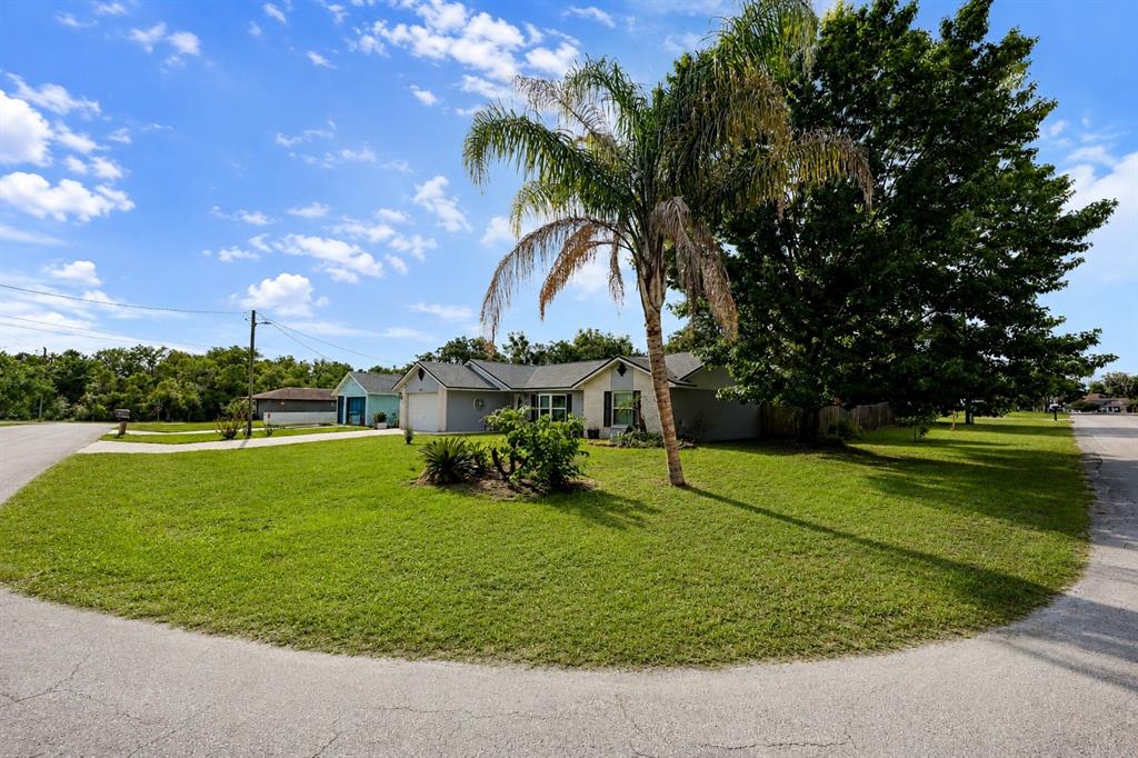 A single-story house with a palm tree in the front yard under a blue sky — 1822 S HOUSTON DR, DELTONA, FL