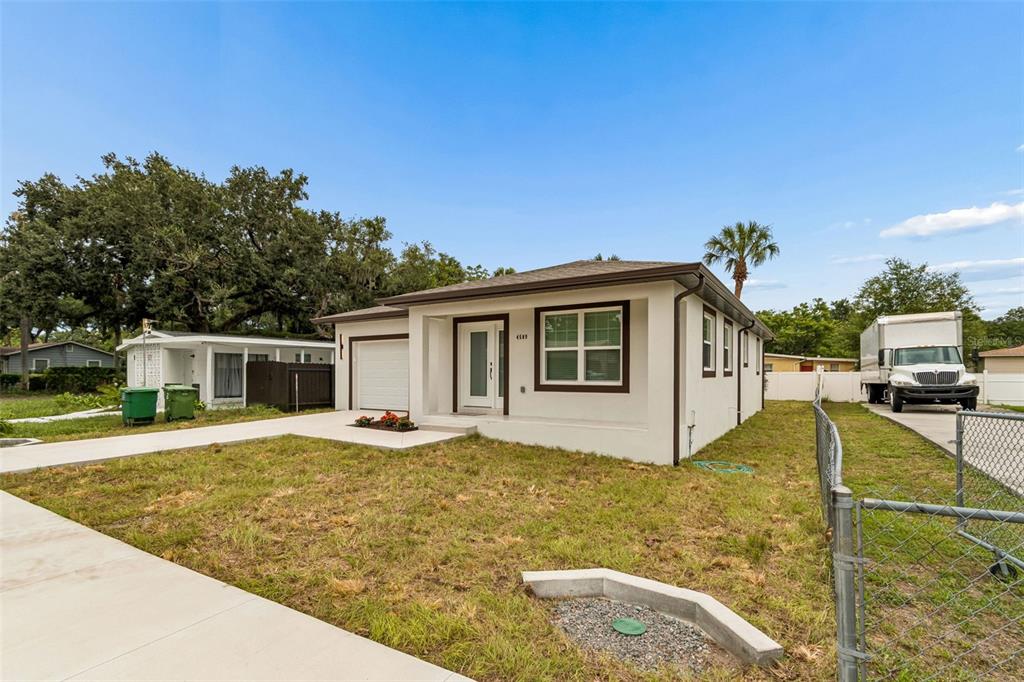 A white single-story house with a brown roof and a concrete driveway sits on grass — 4509 N 39TH STREET, TAMPA, FL