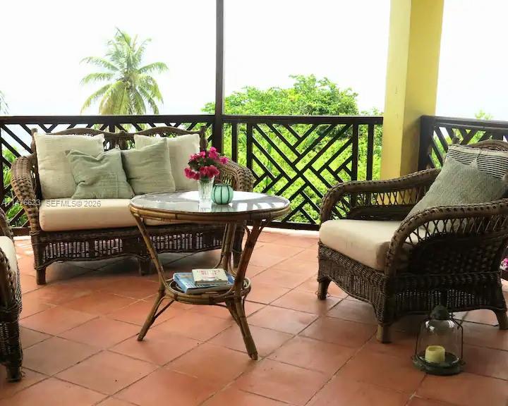 A wicker patio set sits on a tiled balcony overlooking a lush green landscape — 0 CALIBISHE, DOMINICA, 00000, FL