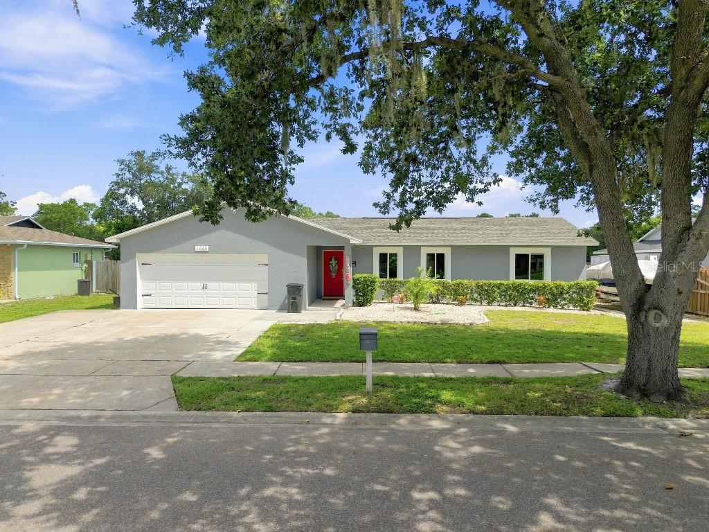 A single-story gray house with a white garage door, red front door, and large oak tree — 1660 GLADIOLAS DRIVE, WINTER PARK, FL