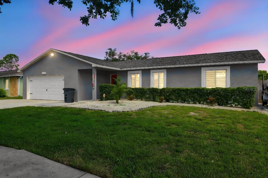 A single-story gray house with a two-car garage and a landscaped front yard at sunset — 1660 GLADIOLAS DRIVE, WINTER PARK, FL