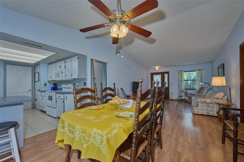 A dining area with a yellow tablecloth sits in front of an open-concept kitchen — 4220 OLEANDER DRIVE, INDIAN LAKE ESTATES, FL