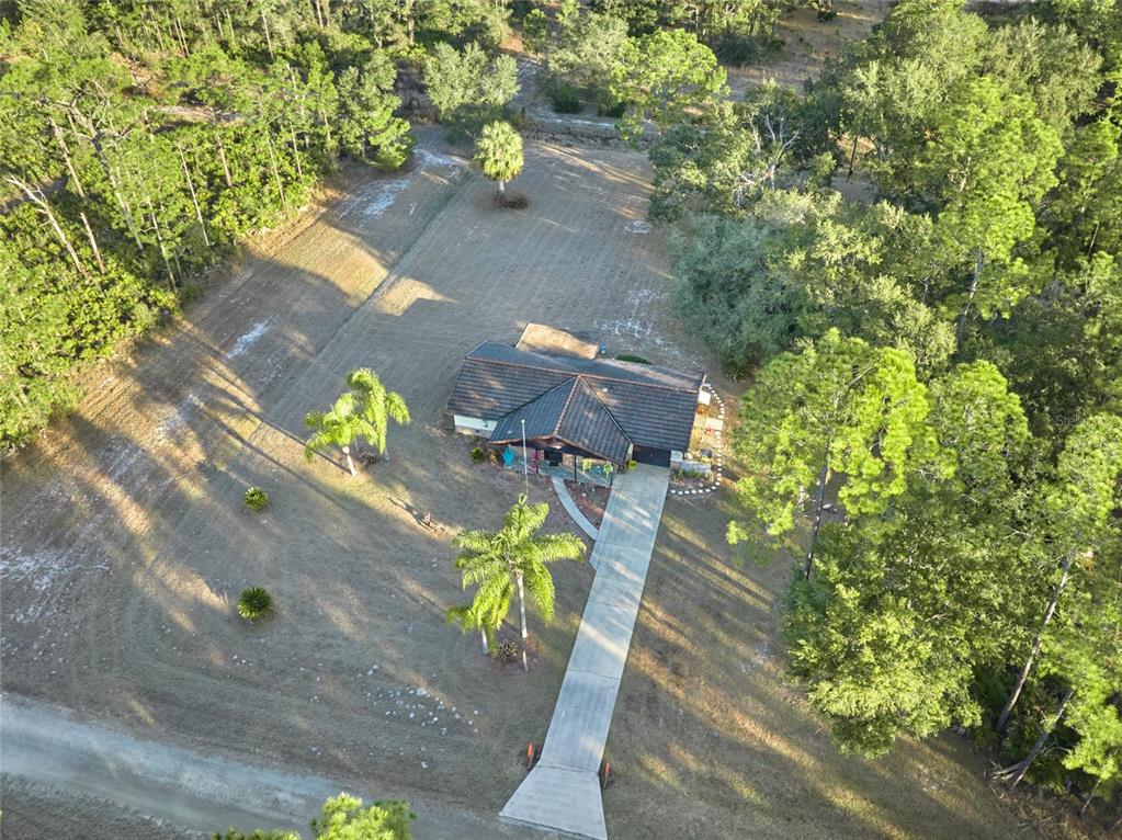 An aerial view shows a house with a dark roof, concrete driveway, and surrounding trees — 4220 OLEANDER DRIVE, INDIAN LAKE ESTATES, FL