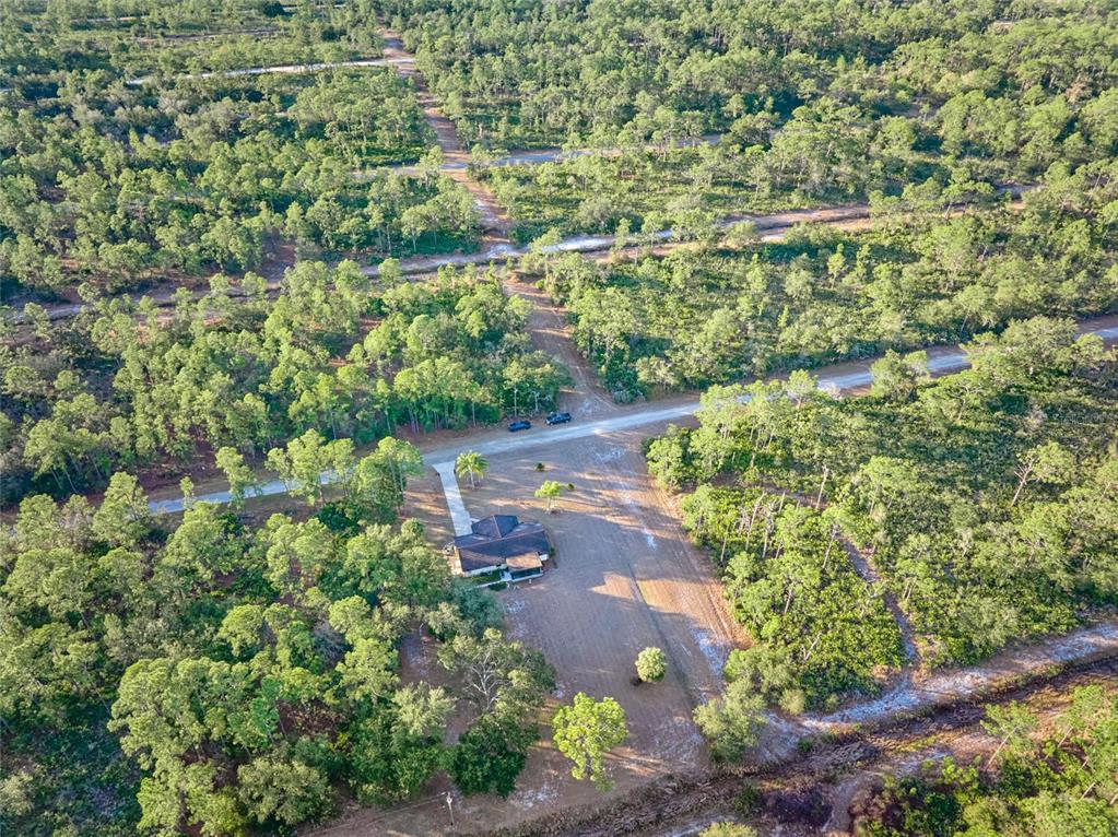 An aerial view shows a house situated on a large, wooded lot with dirt roads — 4220 OLEANDER DRIVE, INDIAN LAKE ESTATES, FL