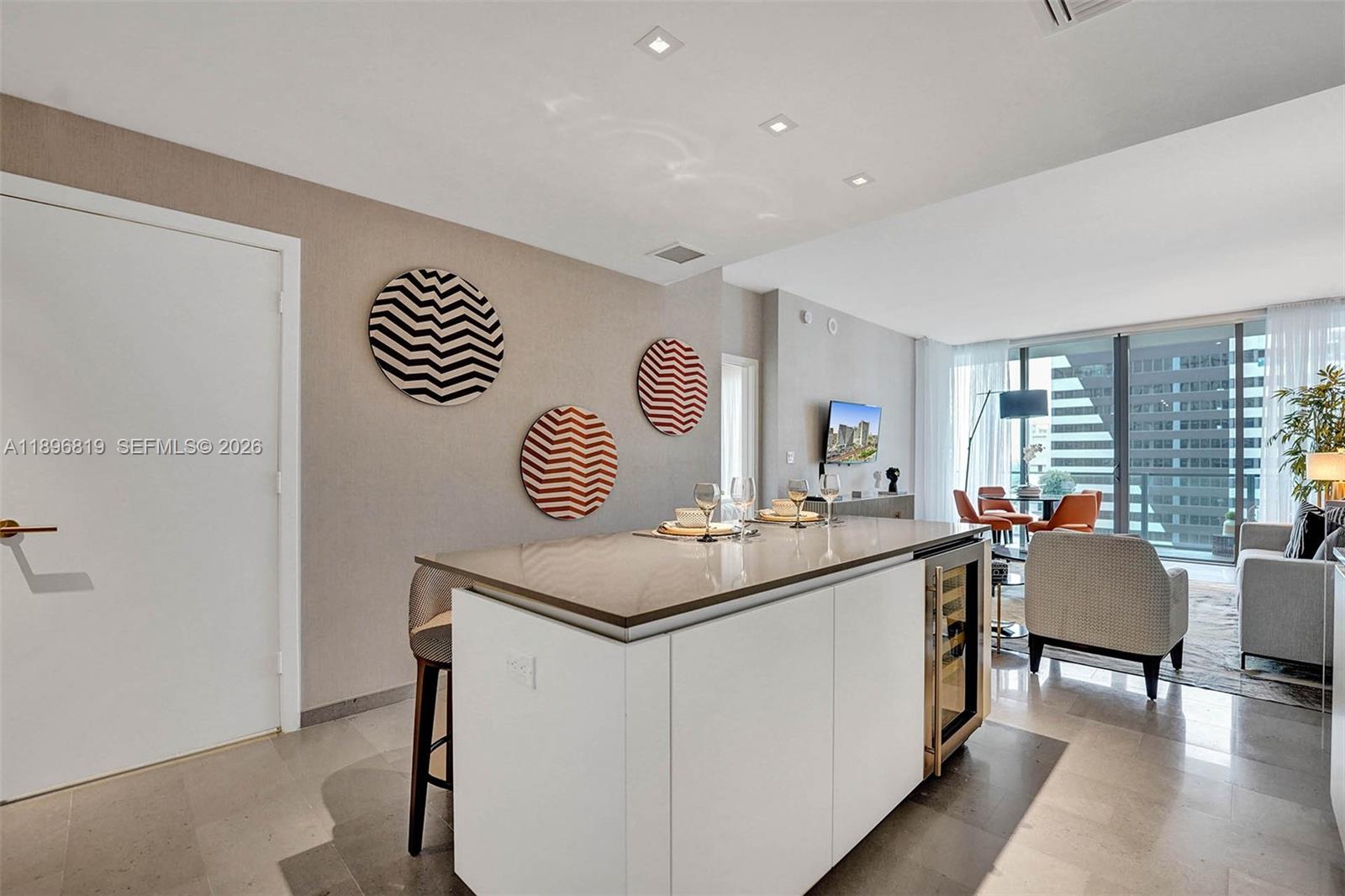 A modern kitchen island with a wine cooler sits in an open-concept living space — 88 SW 7th St # 1408, Miami FL 33130, MIAMI, FL