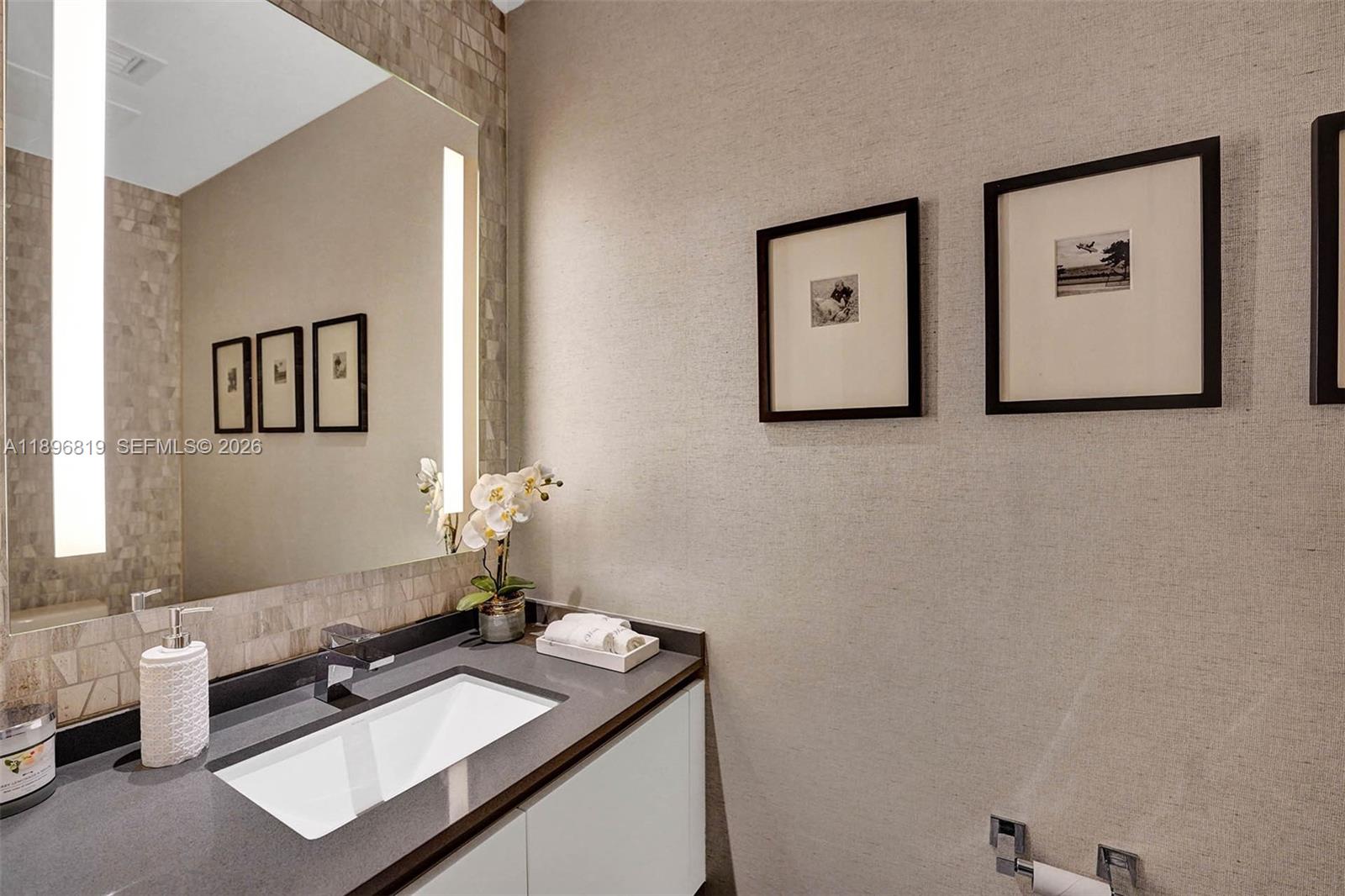 A modern bathroom features a white vanity, dark countertop, large mirror, and framed wall art — 88 SW 7th St # 1408, Miami FL 33130, MIAMI, FL