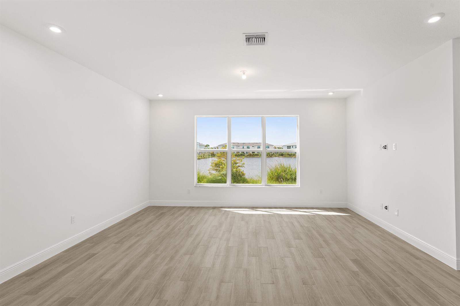 An empty room with white walls, light wood-look flooring, and a large window overlooking water — 1439 NW Corteal Way, Jensen Beach FL 34957, JENSEN BEACH, FL