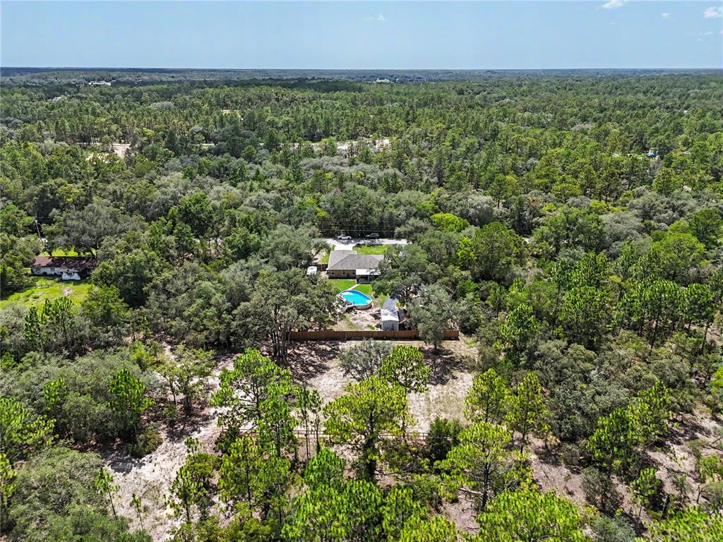 An aerial view shows a house with a pool surrounded by a dense forest — 4171 SW SHASTA COURT, DUNNELLON, FL
