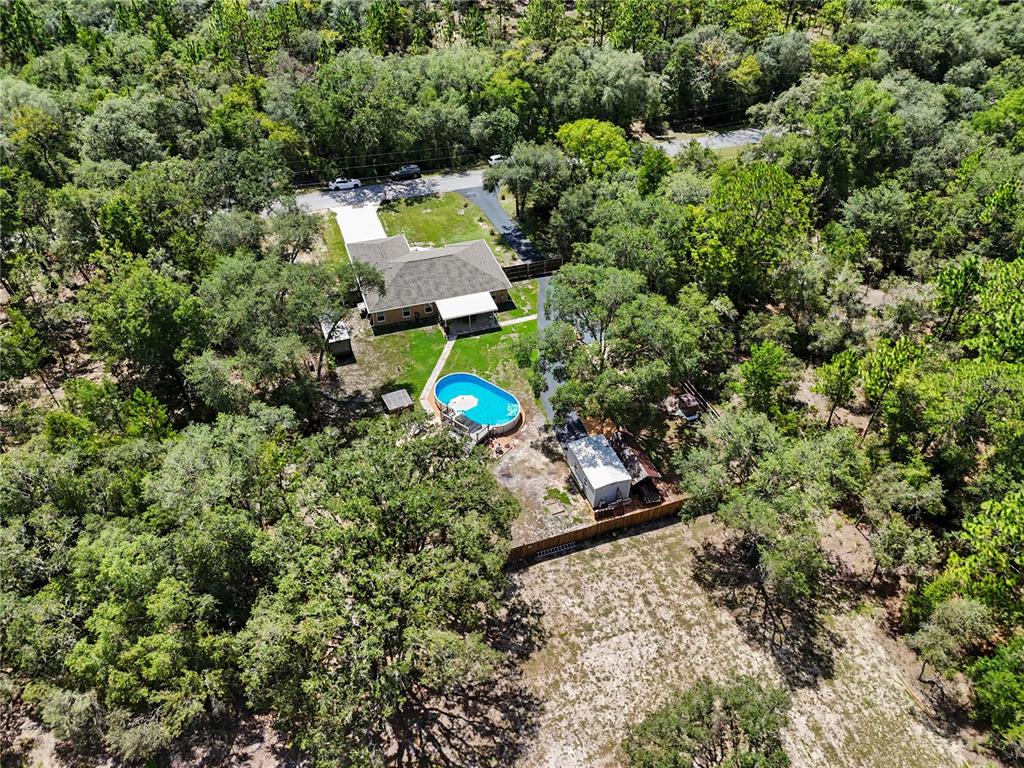 An aerial view shows a house with a pool, driveway, and shed surrounded by trees — 4171 SW SHASTA COURT, DUNNELLON, FL