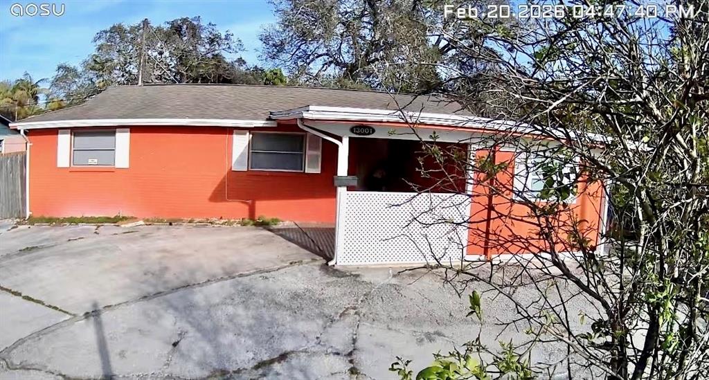 A single-story orange house features a covered front porch with white lattice screening — 13001 120TH STREET, SEMINOLE, FL