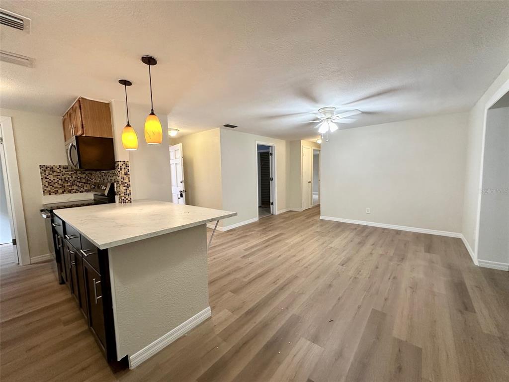 A kitchen with a white island and dark cabinets opens into a living area — 13001 120TH STREET, SEMINOLE, FL