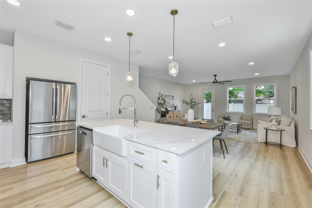 A modern kitchen with white cabinetry and a large island overlooks an open-concept living area — 1911 W BEACH STREET, TAMPA, FL