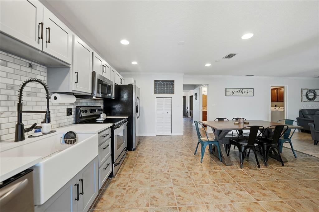 A kitchen with white cabinets, a farmhouse sink, and a dining area with a wooden table — 4053 PINSTAR TERRACE, NORTH PORT, FL