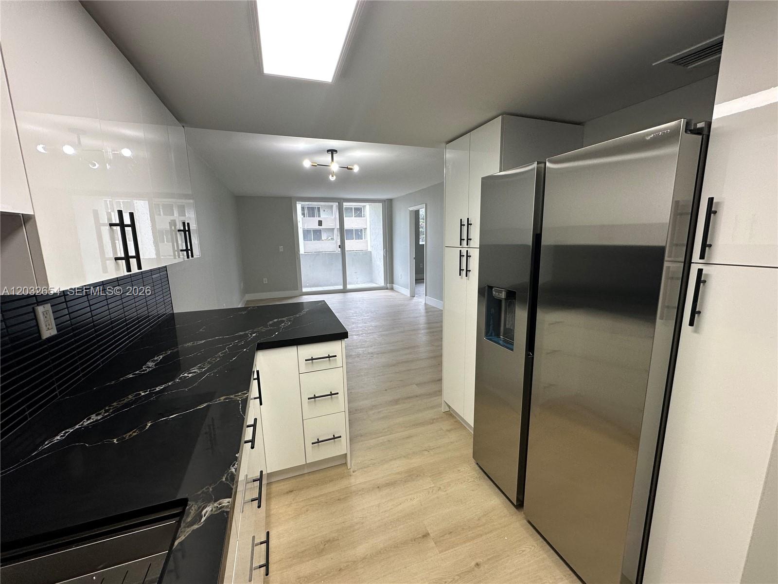 A modern kitchen features white cabinets, black marble countertops, and stainless steel appliances — 10090 NW 80th Ct # 1325, Hialeah Gardens FL 33016, HIALEAH GARDENS, FL