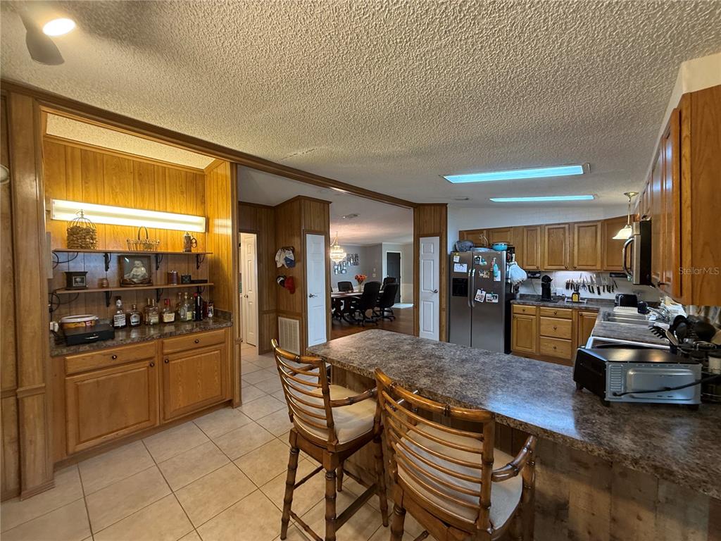 A kitchen features wood cabinets, a breakfast bar, and an adjacent wet bar area — 802 ROBIN LANE, WILDWOOD, FL