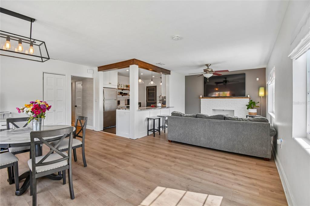 An open-concept living room and kitchen featuring wood-look flooring, a brick fireplace, and dining area — 259 ORANGE TERRACE DRIVE, WINTER PARK, FL