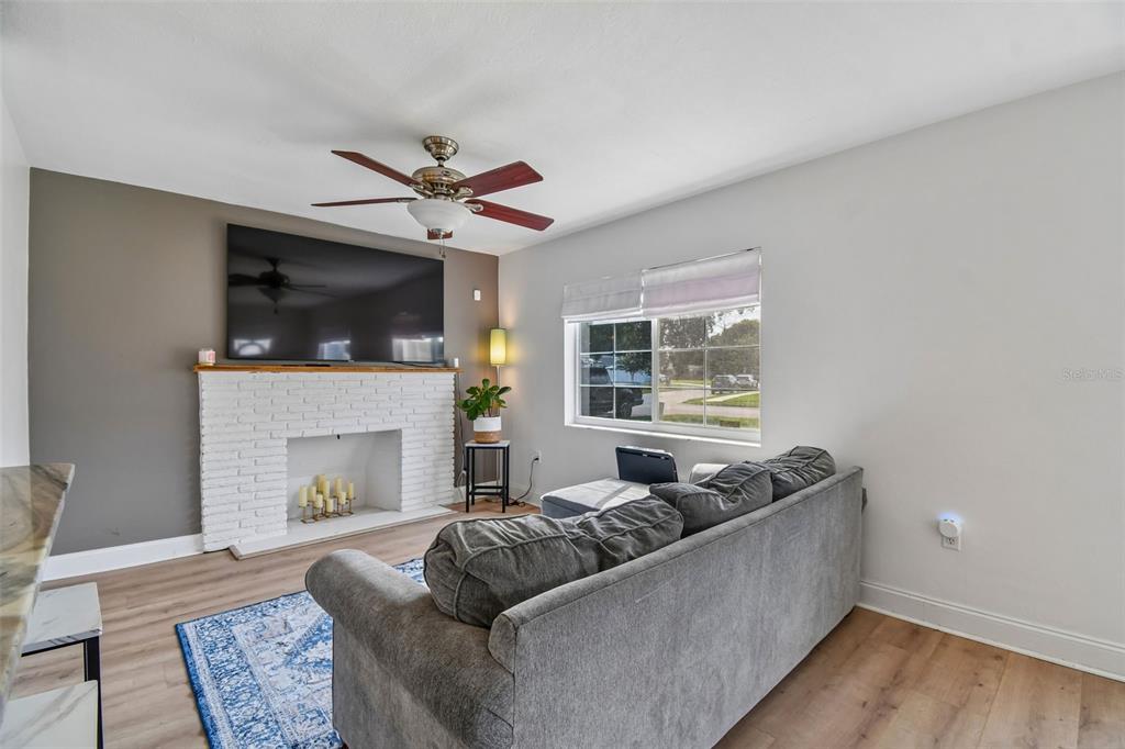 A living room features a white brick fireplace, a wall-mounted television, and a gray sofa — 259 ORANGE TERRACE DRIVE, WINTER PARK, FL