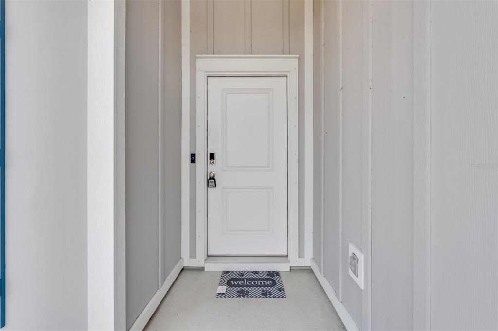 A white front door with a welcome mat sits in a gray-walled entryway — 274 BAYOU BEND LANE, PANAMA CITY, FL