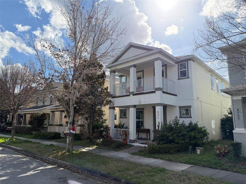 A two-story house with a white exterior, front porches, and a balcony on a street — 8272 BRYCE CANYON AVENUE, WINDERMERE, FL