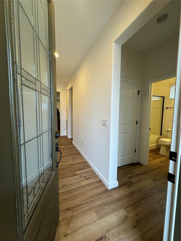 A view from an open front door into a hallway with wood-look flooring and bathroom — 3339 NW 52ND AVENUE ROAD, OCALA, FL