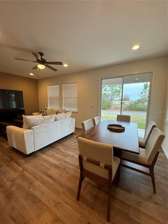 A living and dining area with wood-look flooring, a ceiling fan, and a sliding glass door — 3339 NW 52ND AVENUE ROAD, OCALA, FL