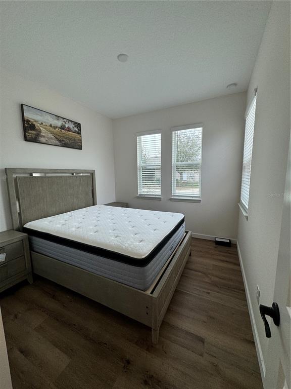 A bedroom features a bed with a gray frame, wood-look flooring, and two windows — 3339 NW 52ND AVENUE ROAD, OCALA, FL