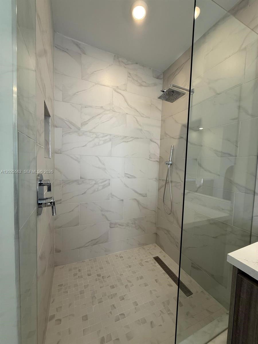 A walk-in shower features white marble-look wall tiles, a mosaic floor, and a glass door — 19616 NE 14th Ct, Miami FL 33179, MIAMI, FL
