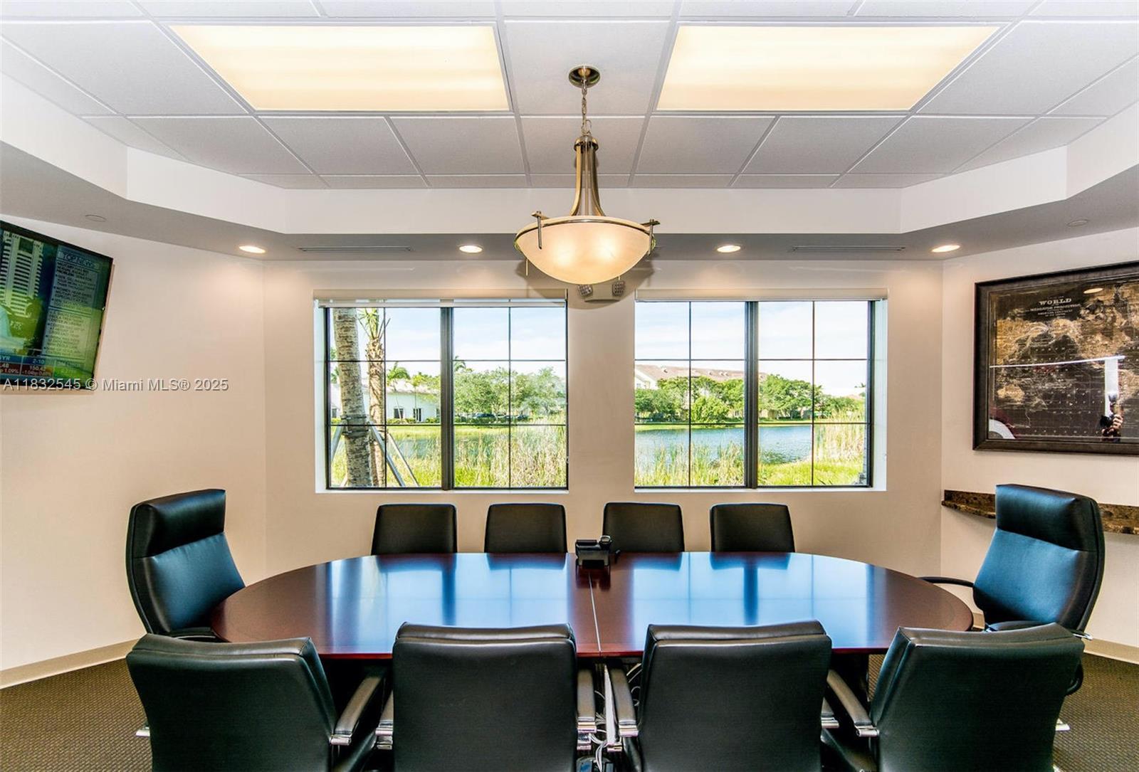 A conference room features a dark wood table, black leather chairs, and windows overlooking water — 1555 Bonaventure Blvd # 2019, Weston FL 33326, WESTON, FL