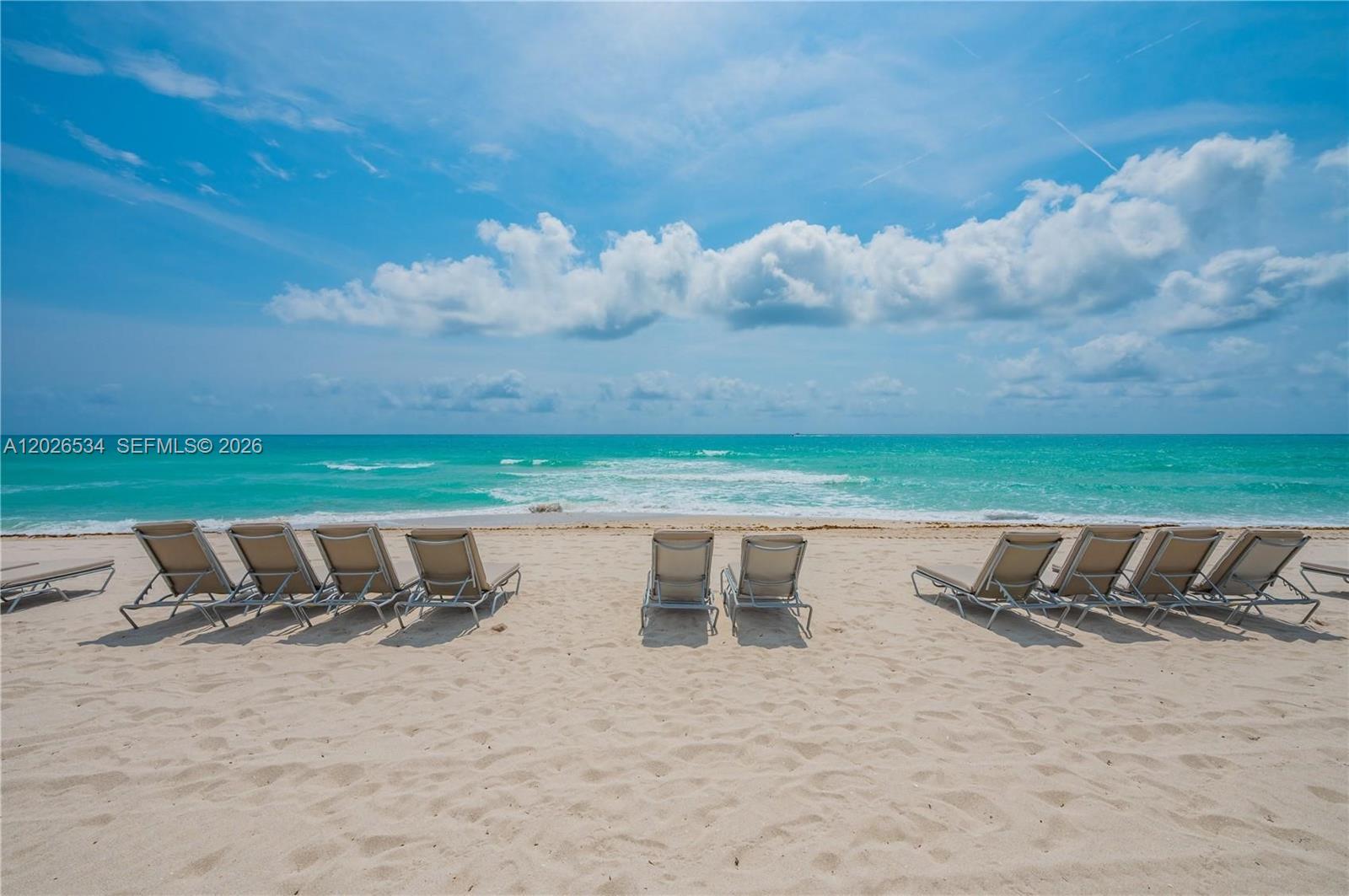 Several lounge chairs are arranged on a sandy beach facing the turquoise ocean — 9801 Collins Ave # 6P, Bal Harbour FL 33154, BAL HARBOUR, FL