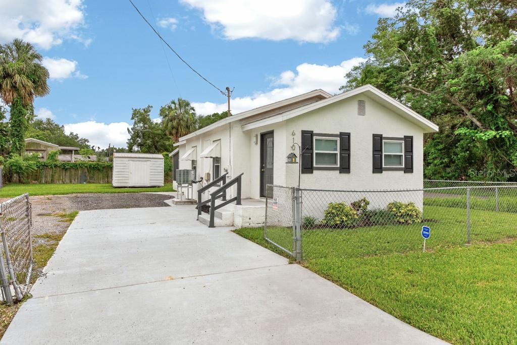 A single-story white house with black shutters, a concrete driveway, and a chain-link fence — 6101 ANNA AVENUE, GIBSONTON, FL