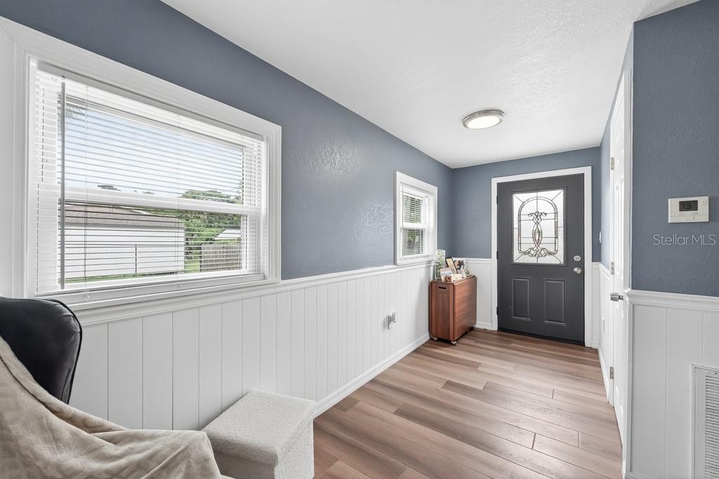 An entryway features blue walls, white wainscoting, wood-look flooring, and a dark front door — 6101 ANNA AVENUE, GIBSONTON, FL