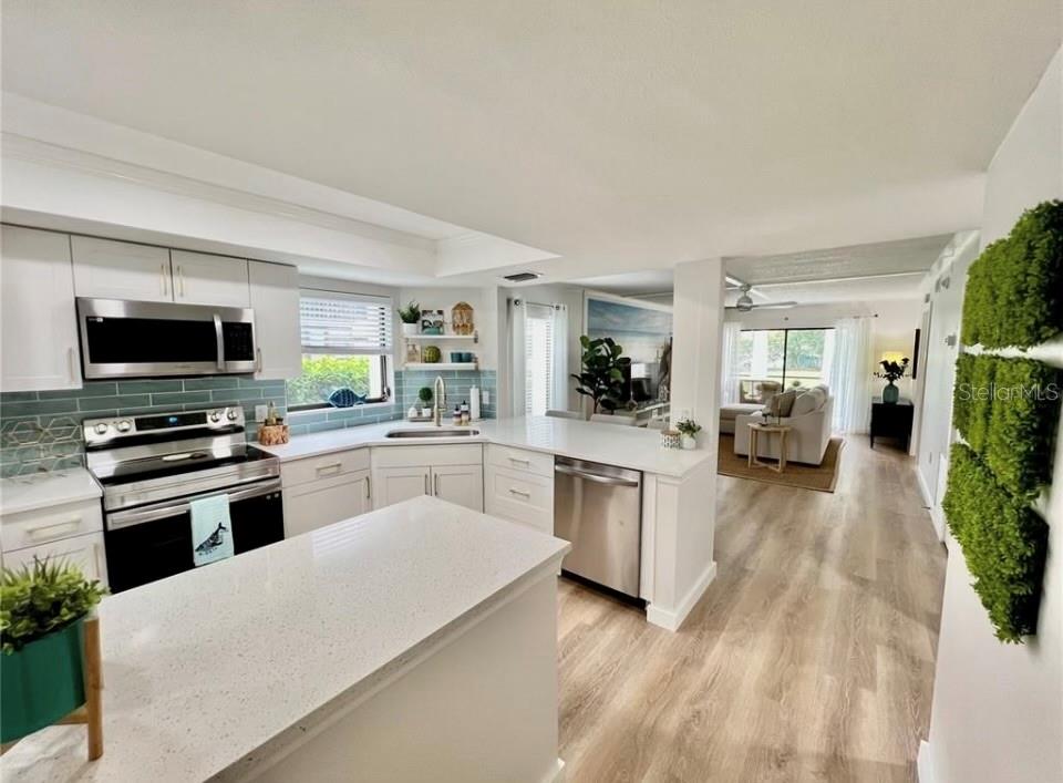 A modern kitchen with white cabinets, stainless steel appliances, and a quartz island countertop — 7203 CURTISS AVENUE UNIT 1A, SARASOTA, FL