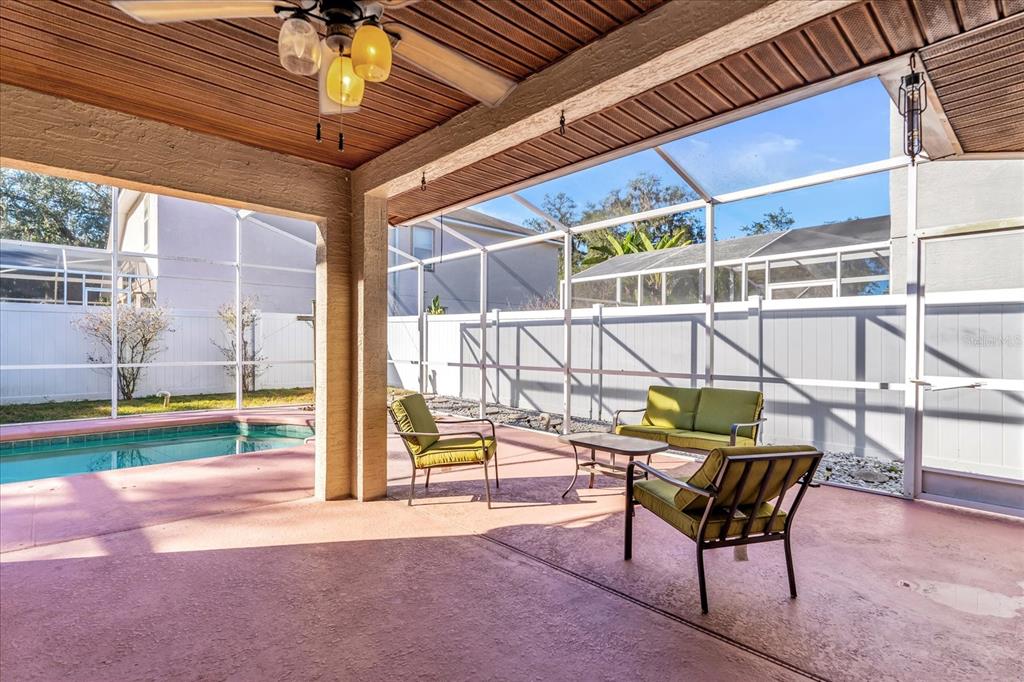 A covered patio with a pool, green outdoor furniture, and a screened-in enclosure — 111 PINEWOOD DRIVE, DAVENPORT, FL