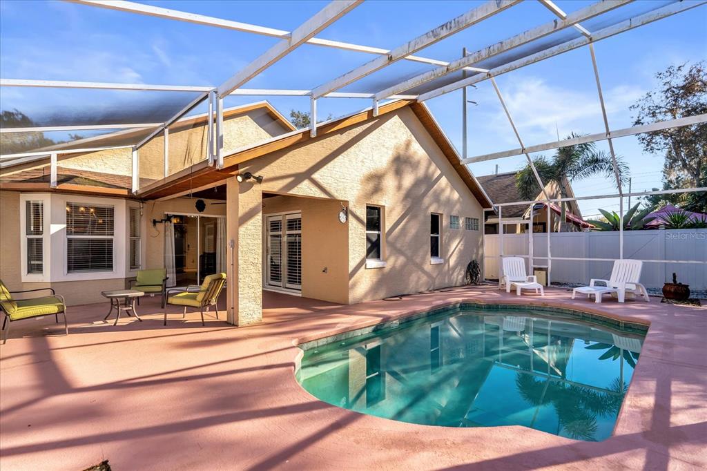 A swimming pool sits on a patio enclosed by a screened-in lanai behind a house — 111 PINEWOOD DRIVE, DAVENPORT, FL