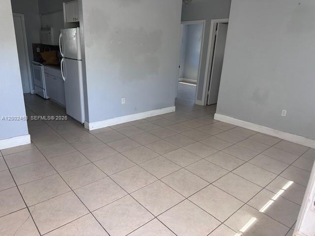 A kitchen area with a white refrigerator and tiled floors opens into a hallway — 3723 NW 23rd Ave # 2, Miami FL 33142, MIAMI, FL