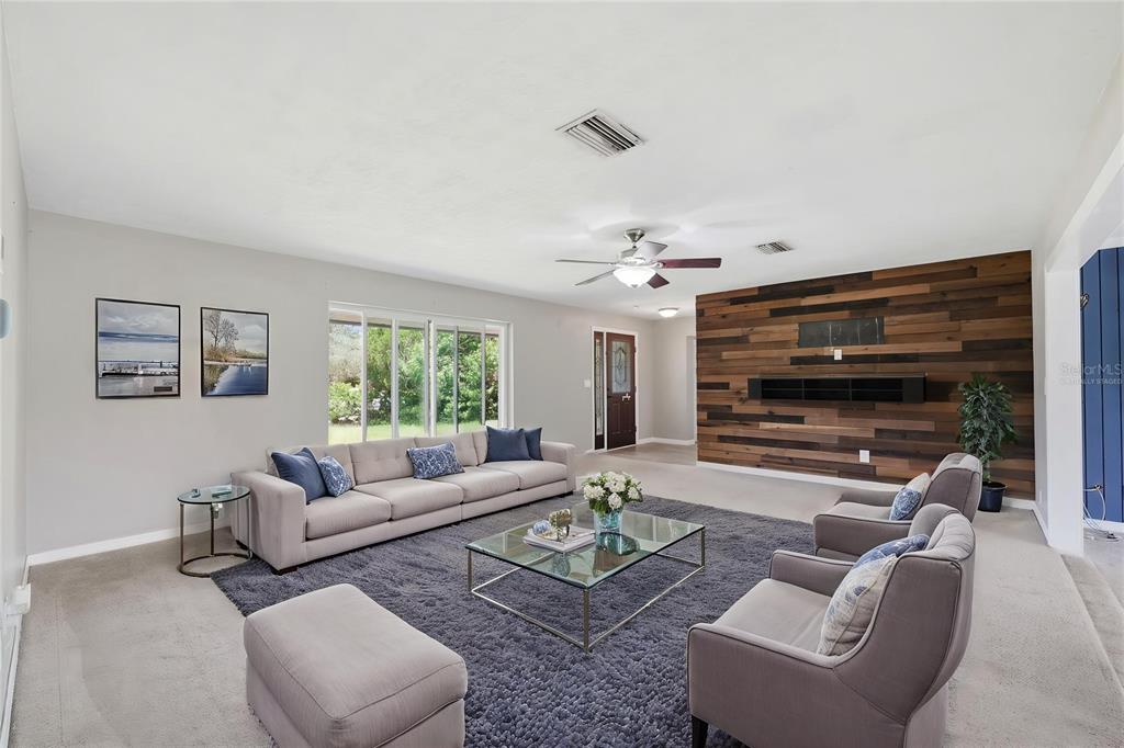 A living room features a large gray sectional, two armchairs, and a wood-paneled accent wall — 459 SAVOY COURT, SPRING HILL, FL