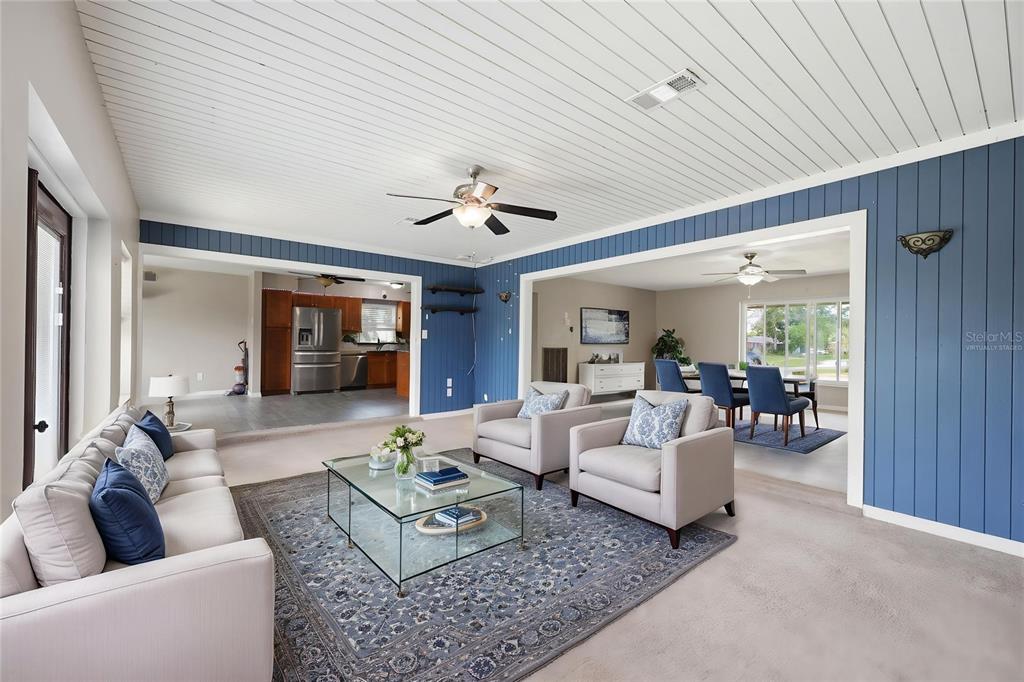 A living room with blue paneled walls, a white slatted ceiling, and beige carpeted floors — 459 SAVOY COURT, SPRING HILL, FL