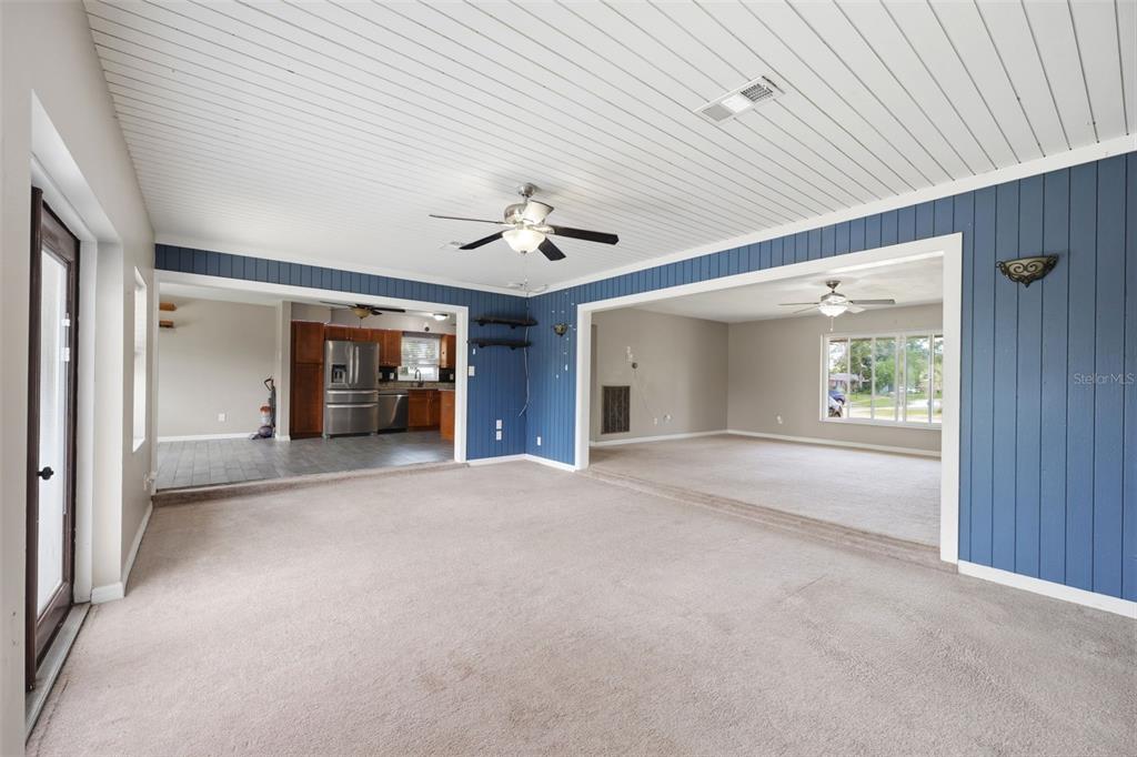 A spacious living area features blue paneled walls, a white slatted ceiling, and carpeted floors — 459 SAVOY COURT, SPRING HILL, FL
