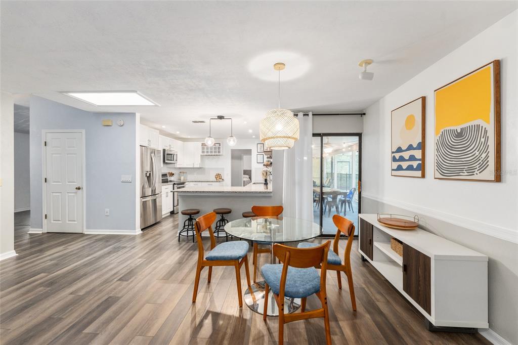 A dining area with a glass table and blue chairs opens to a modern kitchen — 8005 SW 47TH COURT, GAINESVILLE, FL