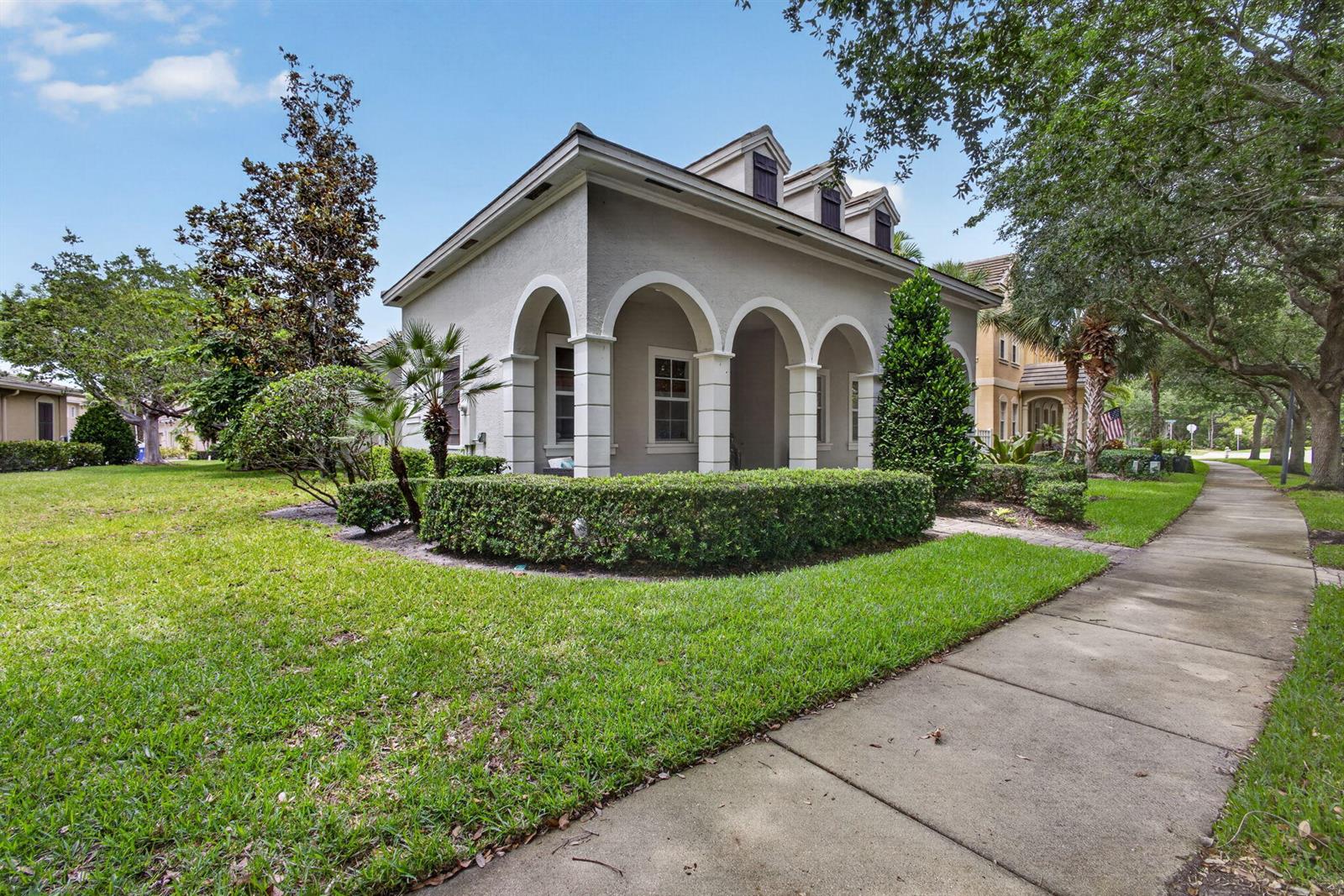 A light-colored house with arched columns and a manicured hedge sits beside a sidewalk — 127 Arklow Avenue, Jupiter FL 33458, JUPITER, FL