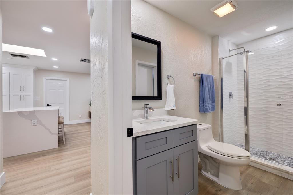 A bathroom with a gray vanity, white countertop, and a glass-enclosed walk-in shower — 490 82ND AVENUE, ST PETE BEACH, FL