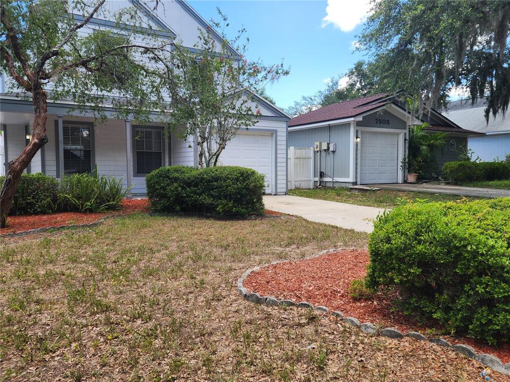 A two-story house with a white garage and a detached garage sits on a lawn — 7507 WAKULLA DRIVE, TEMPLE TERRACE, FL