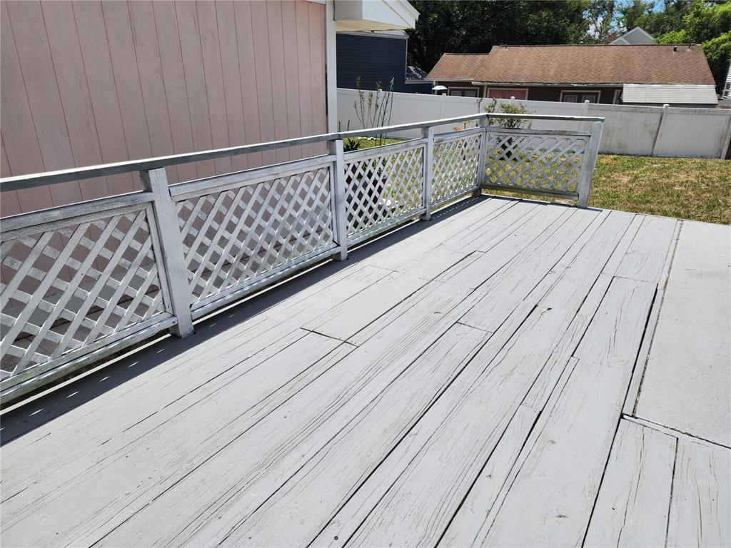 A gray wooden deck features white lattice railings and overlooks a fenced backyard — 7507 WAKULLA DRIVE, TEMPLE TERRACE, FL