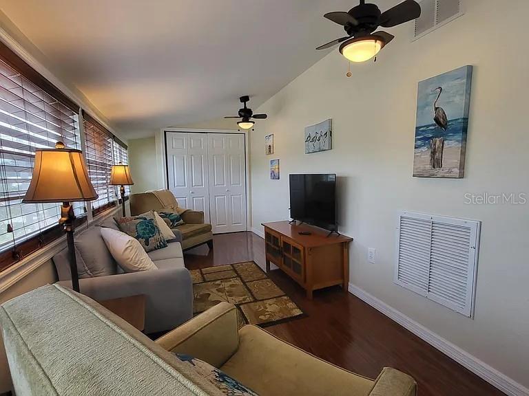 A living room features hardwood floors, a television on a wooden stand, and ceiling fans — 232 CYPRESS STREET, TARPON SPRINGS, FL