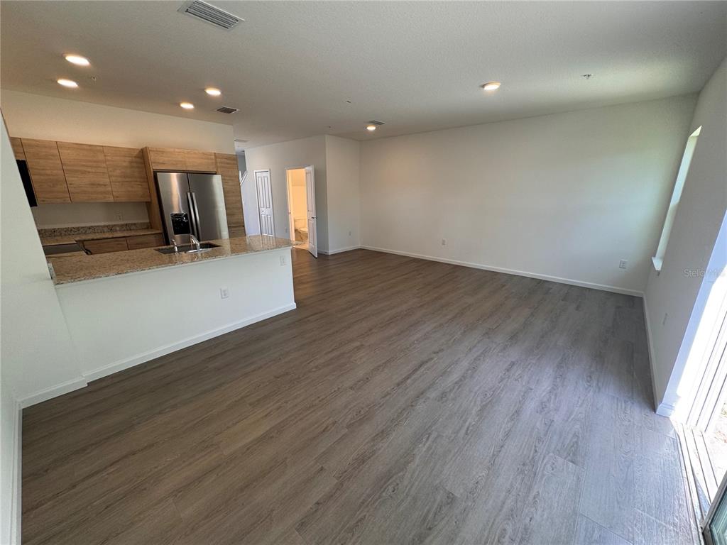 An open-concept kitchen with light wood cabinets and a granite island overlooks a living area — 1209 SOUTHSTATION PLACE UNIT 303, ORLANDO, FL