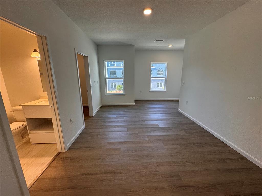 An interior view shows a room with wood-look flooring, two windows, and an adjacent bathroom — 1209 SOUTHSTATION PLACE UNIT 303, ORLANDO, FL