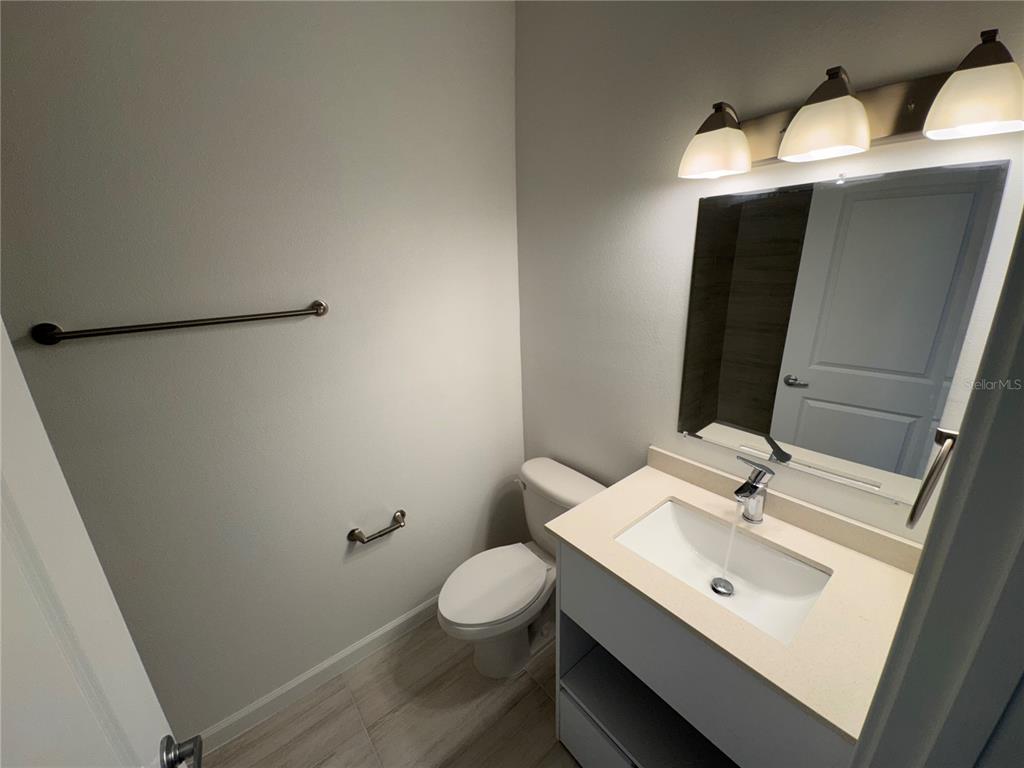 A small bathroom features a vanity with a sink, a toilet, and a wall-mounted towel bar — 1209 SOUTHSTATION PLACE UNIT 303, ORLANDO, FL