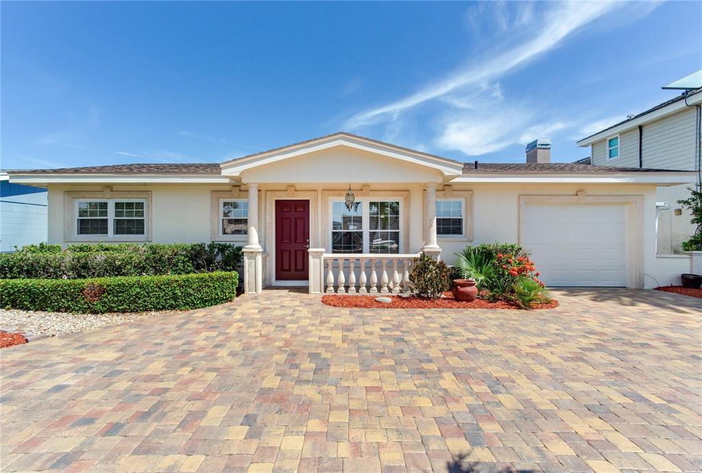 A single-story house with a paved driveway, a red front door, and a balustrade porch — 324 173RD AVENUE E, NORTH REDINGTON BEACH, FL