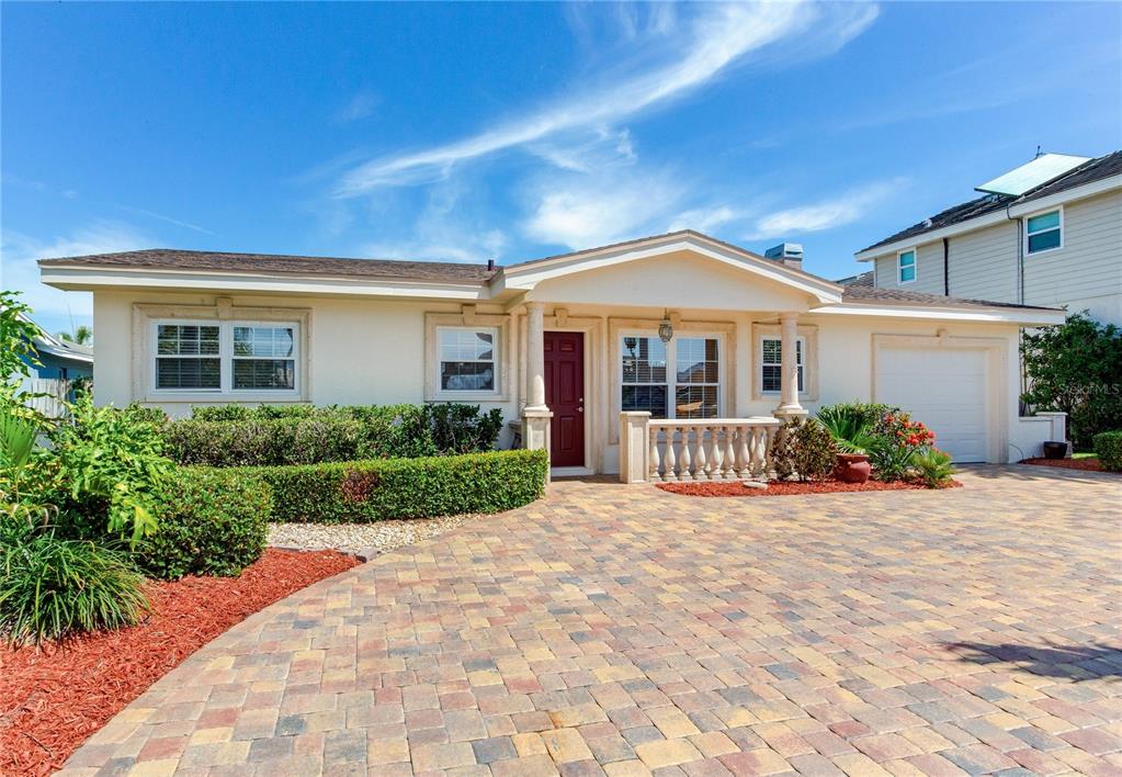 A single-story house with a paved driveway, a red front door, and a small porch — 324 173RD AVENUE E, NORTH REDINGTON BEACH, FL